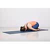 Beautiful sporty fit yogini woman practices yoga asana balasana (child's pose) - resting pose or counter asana for many asanas in studio