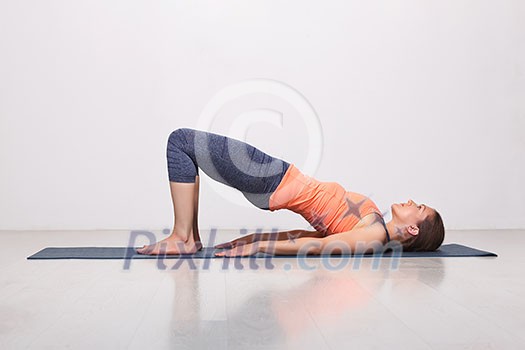Beautiful sporty fit yogini woman practices yoga asana setu bandhasana - bridge pose beginner variation in studio Beautiful sporty fit yogini woman practices yoga asana setu bandhasana - bridge pose beginner variation in studio