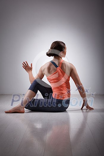 Beautiful sporty fit yogini woman practices yoga asana ardha matsyendrasana - half spinal twist pose Beautiful sporty fit yogini woman practices yoga asana ardha matsyendrasana - half spinal twist pose