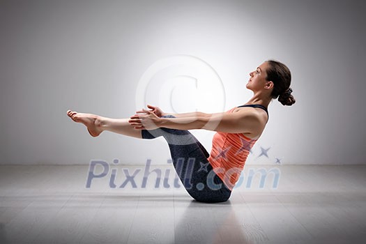 Beautiful sporty fit yogini woman practices yoga asana Paripurna navasana - boat pose beginner variation Beautiful sporty fit yogini woman practices yoga asana Paripurna navasana - boat pose beginner variation