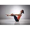 Beautiful sporty fit yogini woman practices yoga asana Paripurna navasana - boat pose beginner variation