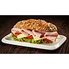 Panorama of ham sandwich with lettuce, cheese, tomato on plate on wooden table