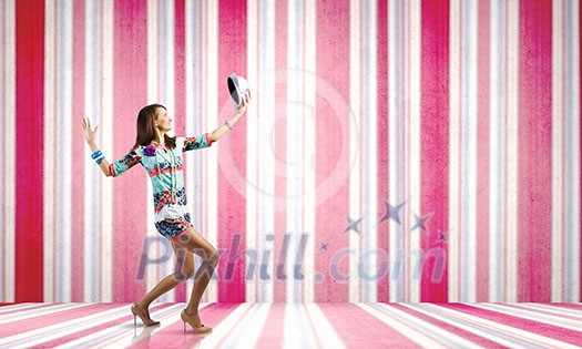 Young woman in colored dress and hat dancing against bokeh background Young woman in colored dress and hat dancing against bokeh background