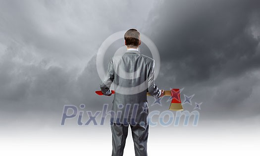 Rear view of young determined businessman with axe in hands Rear view of young determined businessman with axe in hands