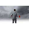 Rear view of young determined businessman with axe in hands