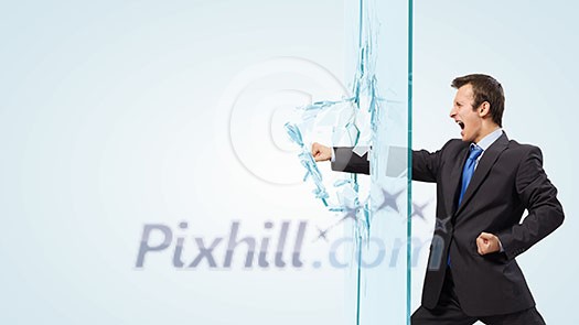 Young determined businessman breaking glass with karate punch Young determined businessman breaking glass with karate punch