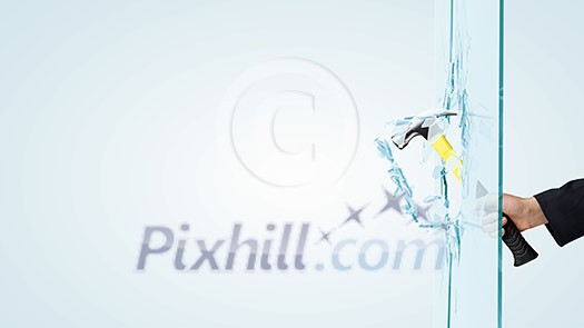 Close up of male hand breaking glass with hammer Close up of male hand breaking glass with hammer