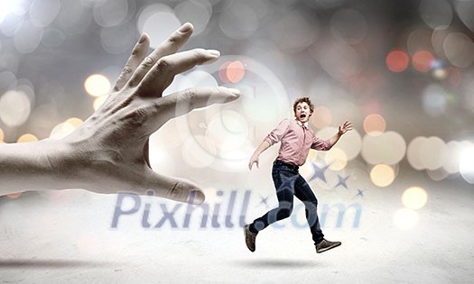 Young man trying to run away from big male hand Young man trying to run away from big male hand