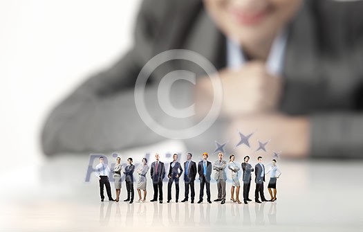 Businesswoman looking at group of businesspeople in miniature Businesswoman looking at group of businesspeople in miniature