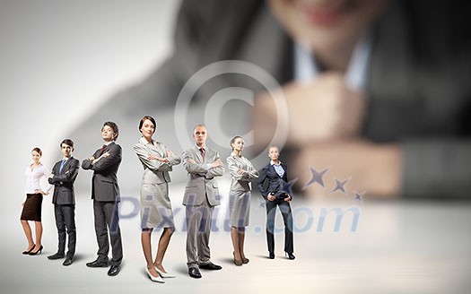 Businesswoman looking at group of businesspeople in miniature Businesswoman looking at group of businesspeople in miniature