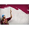 Young woman painting wall in colors with brush