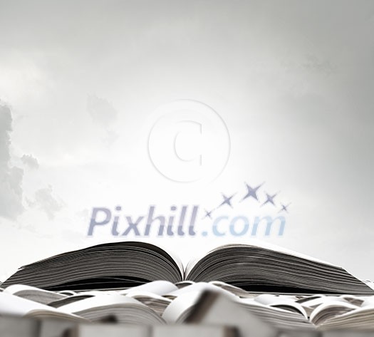 Opened book among many others on sky background Opened book among many others on sky background