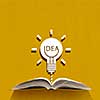 Opened book and idea light bulb on pages