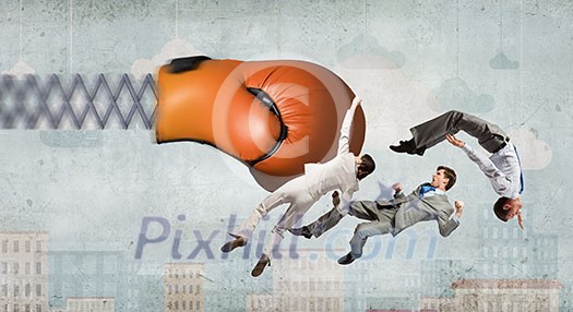 Boxing glove on spring striking group of businesspeople Boxing glove on spring striking group of businesspeople