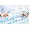 Businessman hand writing with pen and digital business infographs