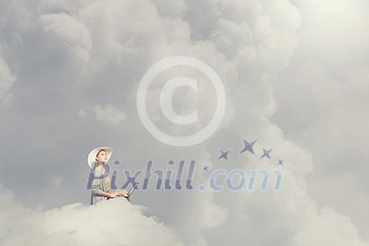 Woman in dress and hat sitting on cloud and working on laptop Woman in dress and hat sitting on cloud and working on laptop