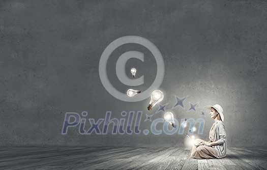 Woman in dress and hat sitting on floor and working on laptop Woman in dress and hat sitting on floor and working on laptop