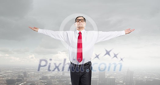Confident businessman with hands spread apart on cityscape background Confident businessman with hands spread apart on cityscape background