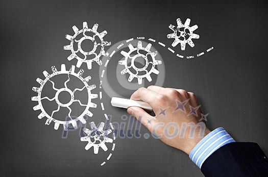 Businessman hand drawing with chalk gears mechanism as teamwork concept Businessman hand drawing with chalk gears mechanism as teamwork concept