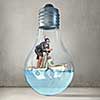 Young businesswoman in suit and diving mask jumping in lightbulb with water