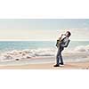 Young man playing saxophone on sea coast
