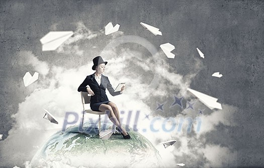 Pretty girl wearing retro hat siting on chair with tablet in hand. Elements of this image are furnished by NASA Pretty girl wearing retro hat siting on chair with tablet in hand. Elements of this image are furnished by NASA