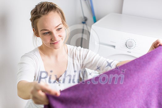 Housework: young woman doing laundry - putting colorful garments into the washing machine (shallow DOF; color toned image) Housework: young woman doing laundry - putting colorful garments into the washing machine (shallow DOF; color toned image)