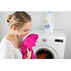 Housework: young woman doing laundry - putting colorful garments into the washing machine (shallow DOF; color toned image)