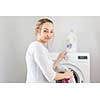 Housework: young woman doing laundry - putting colorful garments into the washing machine (shallow DOF; color toned image)