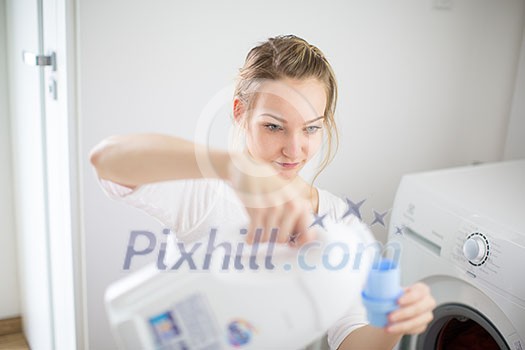 Housework: young woman doing laundry - putting colorful garments into the washing machine (shallow DOF; color toned image) Housework: young woman doing laundry - putting colorful garments into the washing machine (shallow DOF; color toned image)