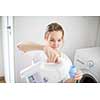 Housework: young woman doing laundry - putting colorful garments into the washing machine (shallow DOF; color toned image)