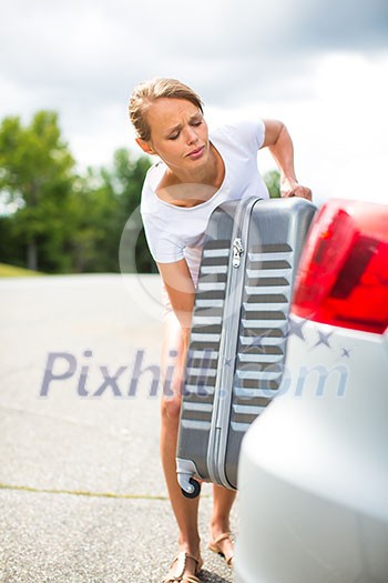 Young woman putting a have suitcase into her car's trunk Young woman putting a have suitcase into her car's trunk