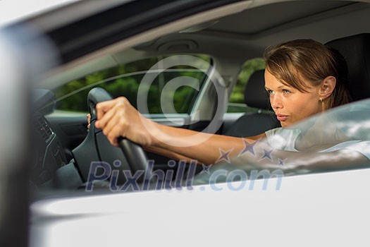 Young woman driving her car, on her way home from work - doing the daily commute Young woman driving her car, on her way home from work - doing the daily commute