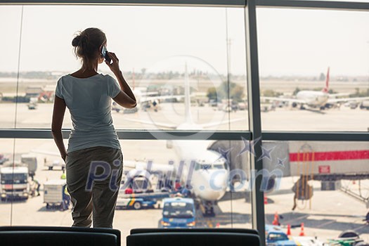 Pretty, young woman waiting at a gate area of a modern airport for the boarding call - making some calls(color toned image; shallow DOF) Pretty, young woman waiting at a gate area of a modern airport for the boarding call - making some calls(color toned image; shallow DOF)