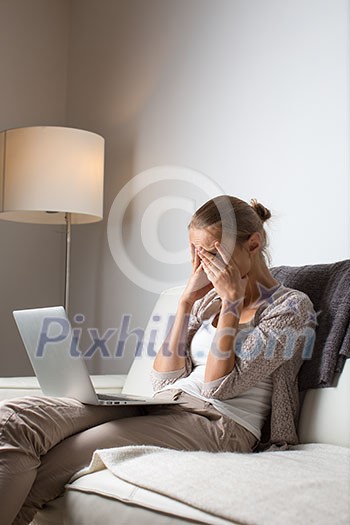 Very tired young woman, burning the midnigh oil - working late at night on her laptop computer, at home, sitting on sofa, rubbing her tired eyes, trying to stay focused Very tired young woman, burning the midnigh oil - working late at night on her laptop computer, at home, sitting on sofa, rubbing her tired eyes, trying to stay focused