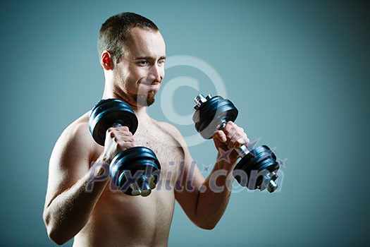 Close up of young man lifting weights over grey background Close up of young man lifting weights over grey background