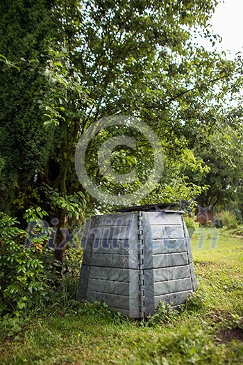 Plastic composter in a garden - filled with decaying organic material to be used as a fertilizer for growing home-grown, organic vegetables (shallow DOF) Plastic composter in a garden - filled with decaying organic material to be used as a fertilizer for growing home-grown, organic vegetables (shallow DOF)
