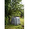 Plastic composter in a garden - filled with decaying organic material to be used as a fertilizer for growing home-grown, organic vegetables (shallow DOF)