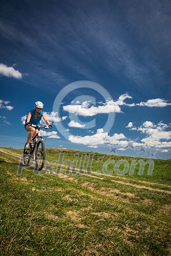 Pretty, young female biker outdoors on her mountain bike (motion blurred image) Pretty, young female biker outdoors on her mountain bike (motion blurred image)