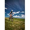 Pretty, young female biker outdoors on her mountain bike (motion blurred image)