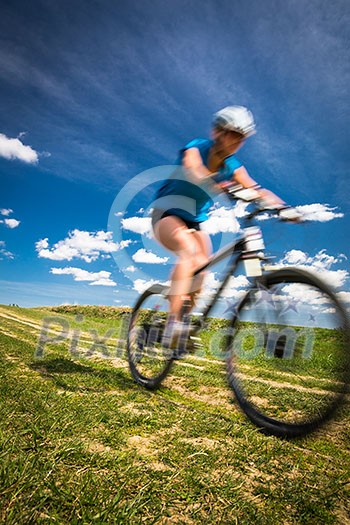 Pretty, young female biker outdoors on her mountain bike (motion blurred image) Pretty, young female biker outdoors on her mountain bike (motion blurred image)