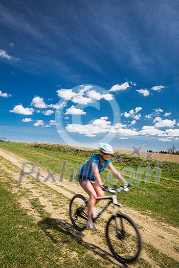 Pretty, young female biker outdoors on her mountain bike (motion blurred image) Pretty, young female biker outdoors on her mountain bike (motion blurred image)