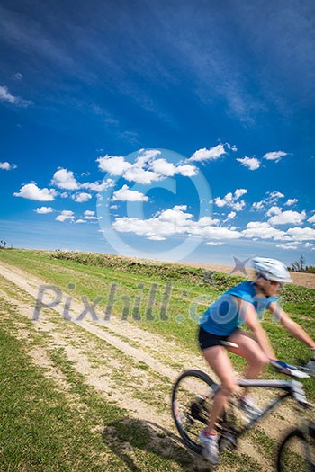 Pretty, young female biker outdoors on her mountain bike (motion blurred image) Pretty, young female biker outdoors on her mountain bike (motion blurred image)