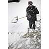 Man shoveling snow from the sidewalk in front of his house after a heavy snowfall in a city