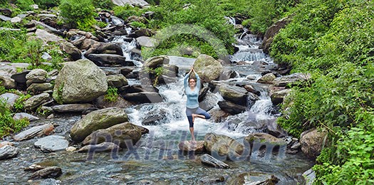 Woman practices balance yoga asana Vrikshasana tree pose at waterfall outdoors. Himachal Pradesh, India. Panorama Woman practices balance yoga asana Vrikshasana tree pose at waterfall outdoors. Himachal Pradesh, India. Panorama