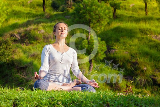 Young sporty fit woman doing yoga outdoors - meditating and relaxing in Padmasana Lotus Pose with chin mudra on green grass in forest Young sporty fit woman doing yoga outdoors - meditating and relaxing in Padmasana Lotus Pose with chin mudra on green grass in forest