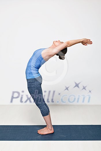 Beautiful sporty fit woman practices Sivananmda yoga asana Anuvittasana - standing back bend pose Beautiful sporty fit woman practices Sivananmda yoga asana Anuvittasana - standing back bend pose