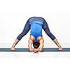Beautiful sporty fit woman practices Ashtanga Vinyasa yoga asana Prasarita padottanasana C - wide legged forward bend C