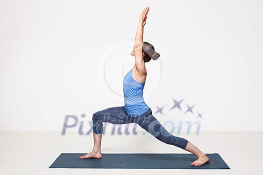 Beautiful sporty fit yogini woman practices yoga asana Virabhadrasana 1 - warrior pose 1 Beautiful sporty fit yogini woman practices yoga asana Virabhadrasana 1 - warrior pose 1