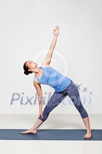 Beautiful sporty fit woman practices yoga asana utthita trikonasana - extended triangle pose beginner variation Beautiful sporty fit woman practices yoga asana utthita trikonasana - extended triangle pose beginner variation
